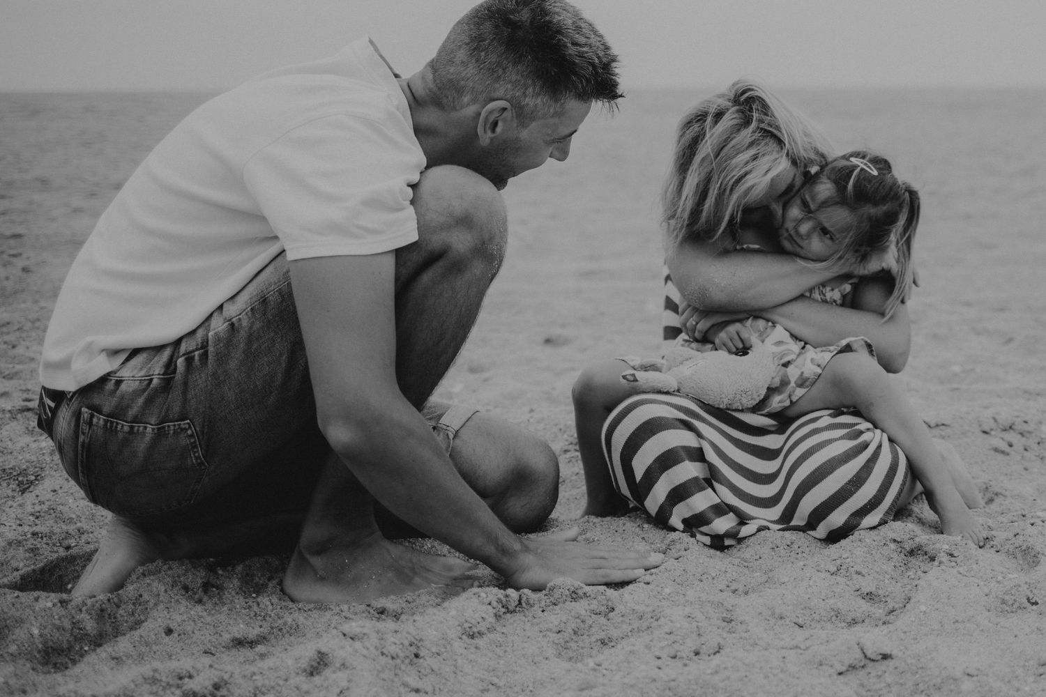 foto preto e Branco na praia do Salgado em Portugal , família sentada na areia durante sessão fotográfica