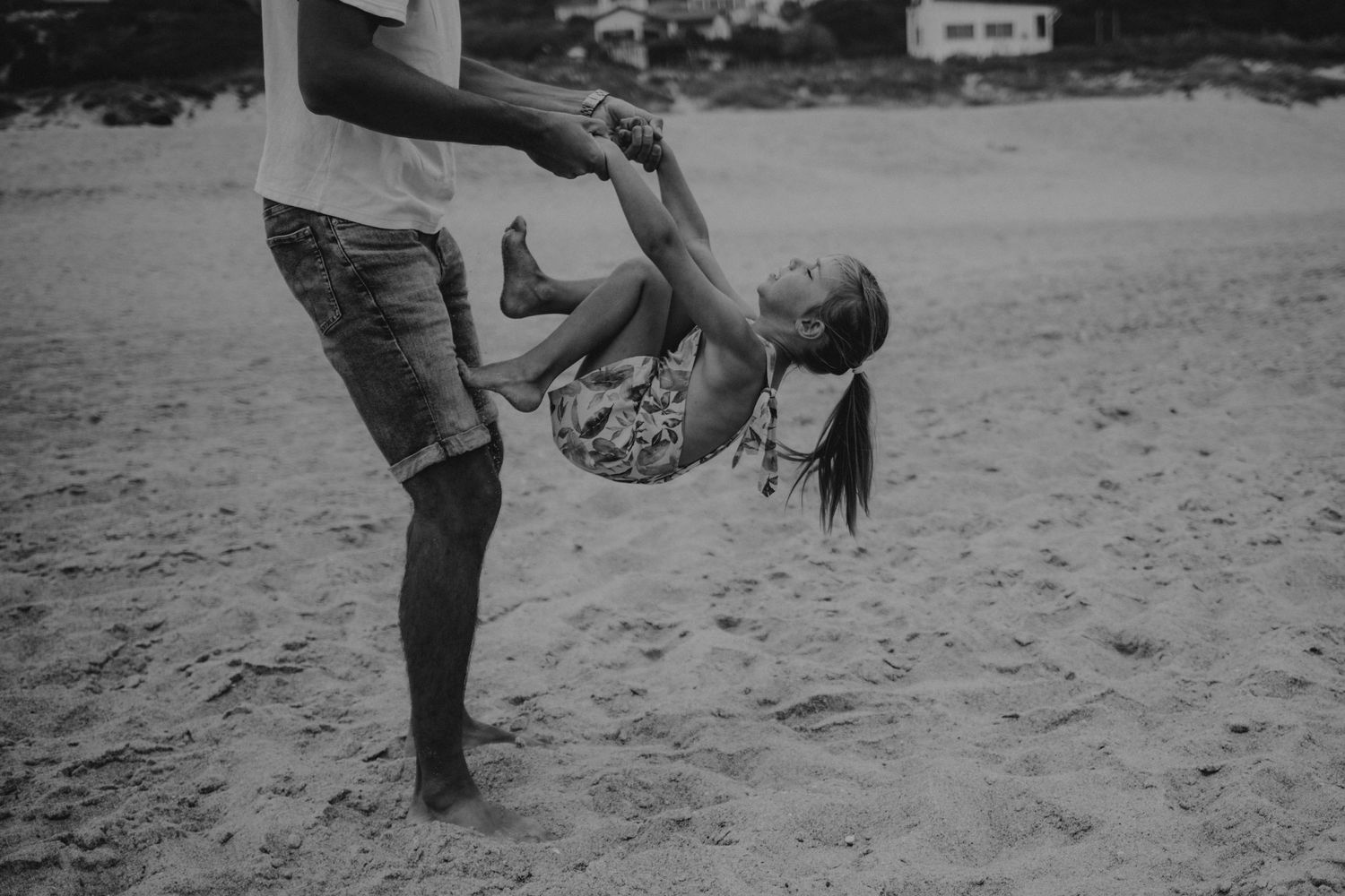 Foto preto e branco na praia do Salgado em Portugal , filha escalando no Pai durante sessão fotográfica  de família