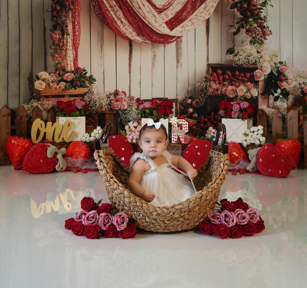 Valentine's day themed newborn photo setup with rustic wooden backdrop, red hearts, and floral decorations.