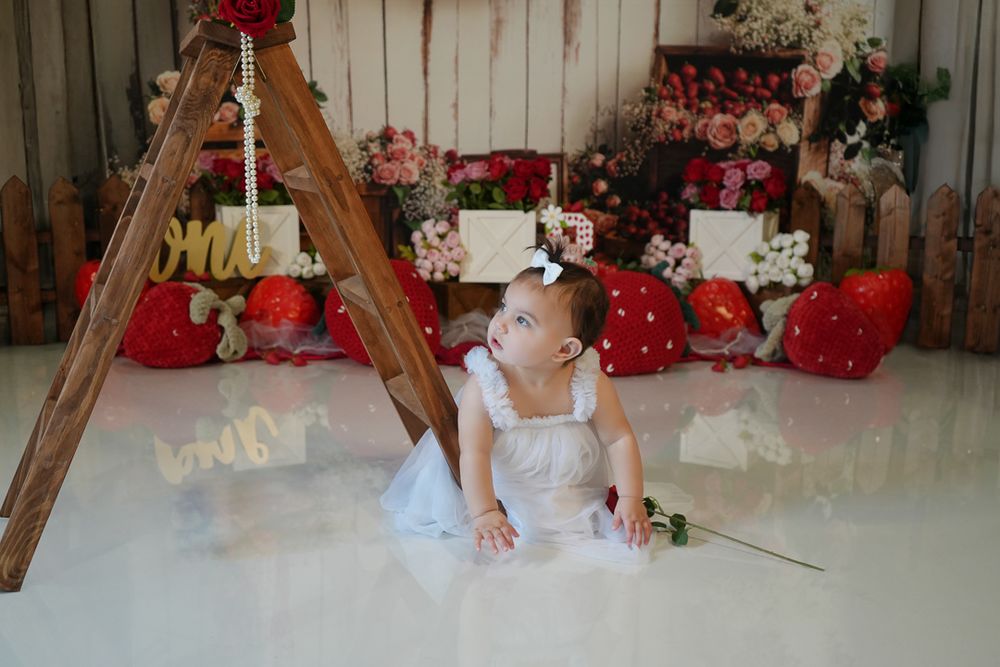 Baby photography scene with rustic wooden props, red valentine hearts, and soft white floor setting.