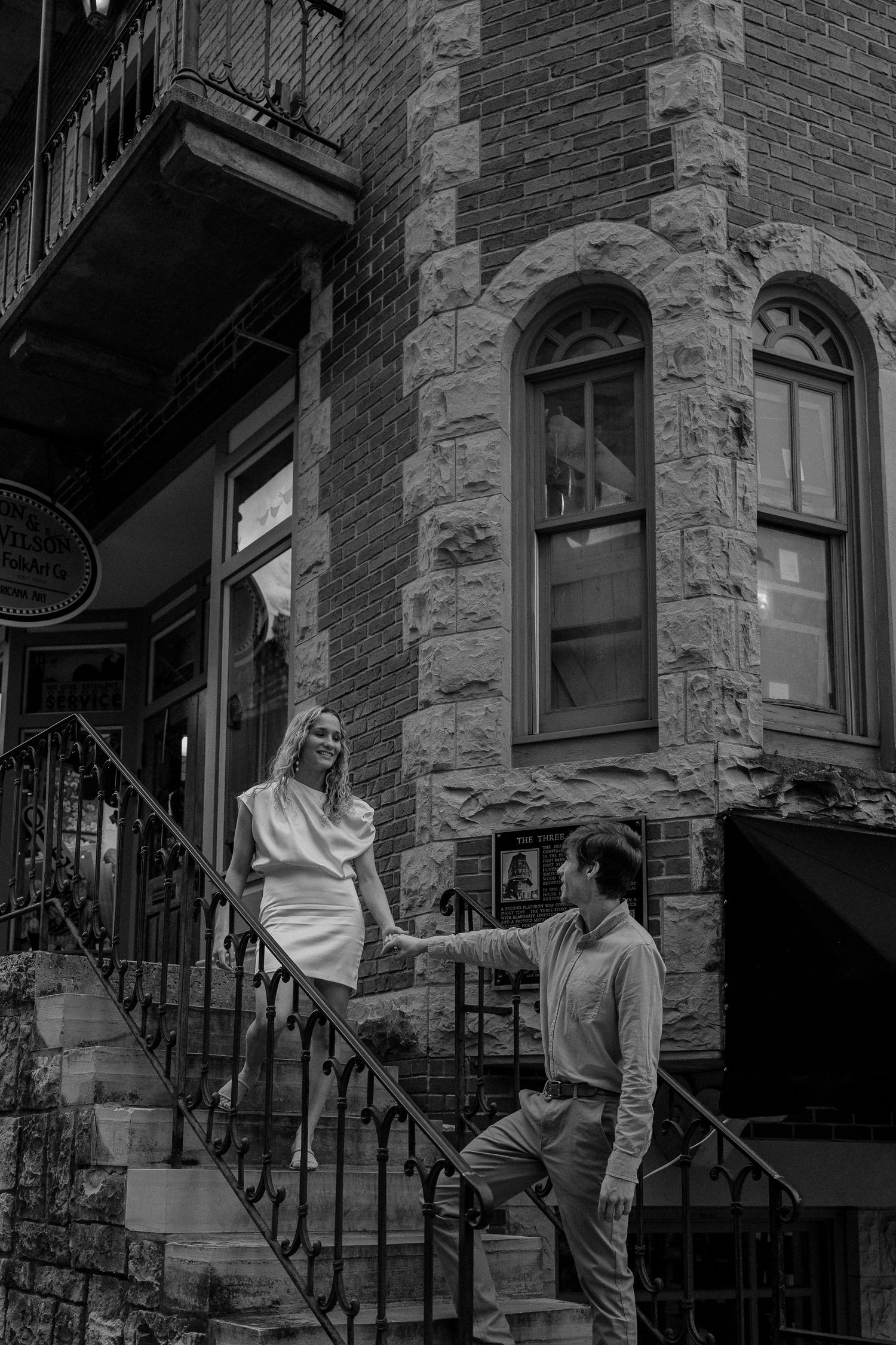 Black and white photo of couple playing on vintage building steps.