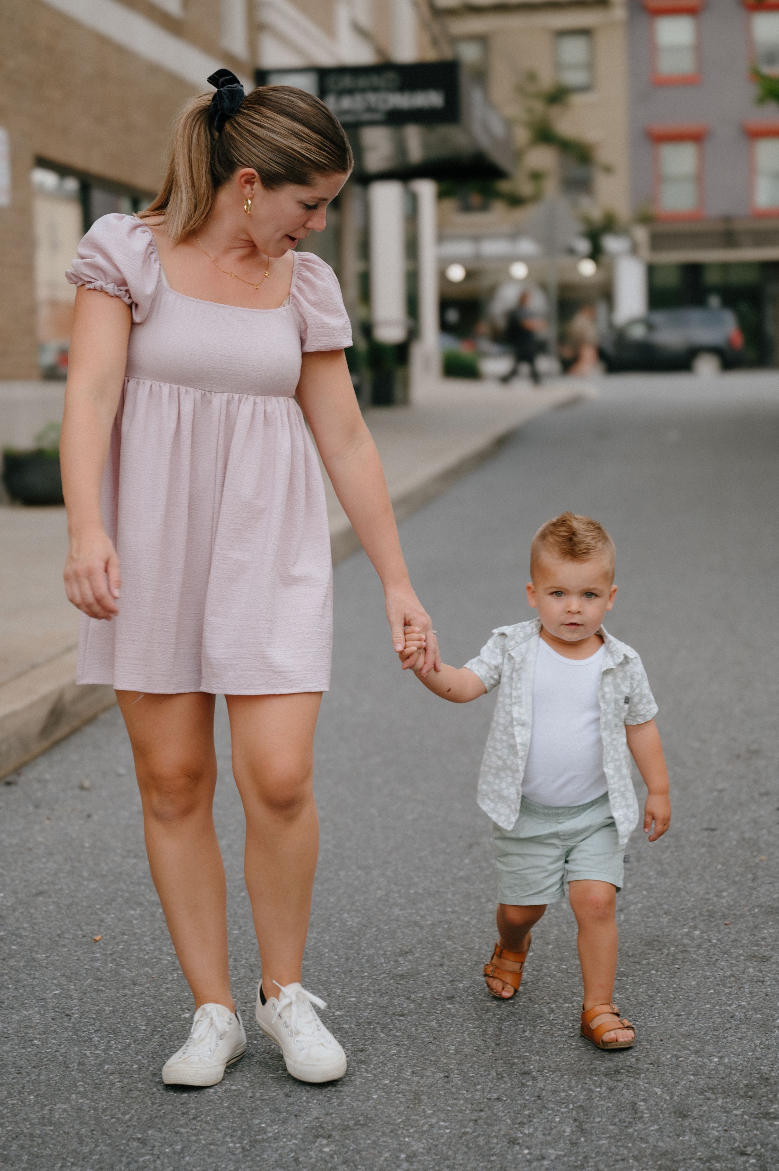 A sweet moment of walking hand in hand down a city street on a sunny day.