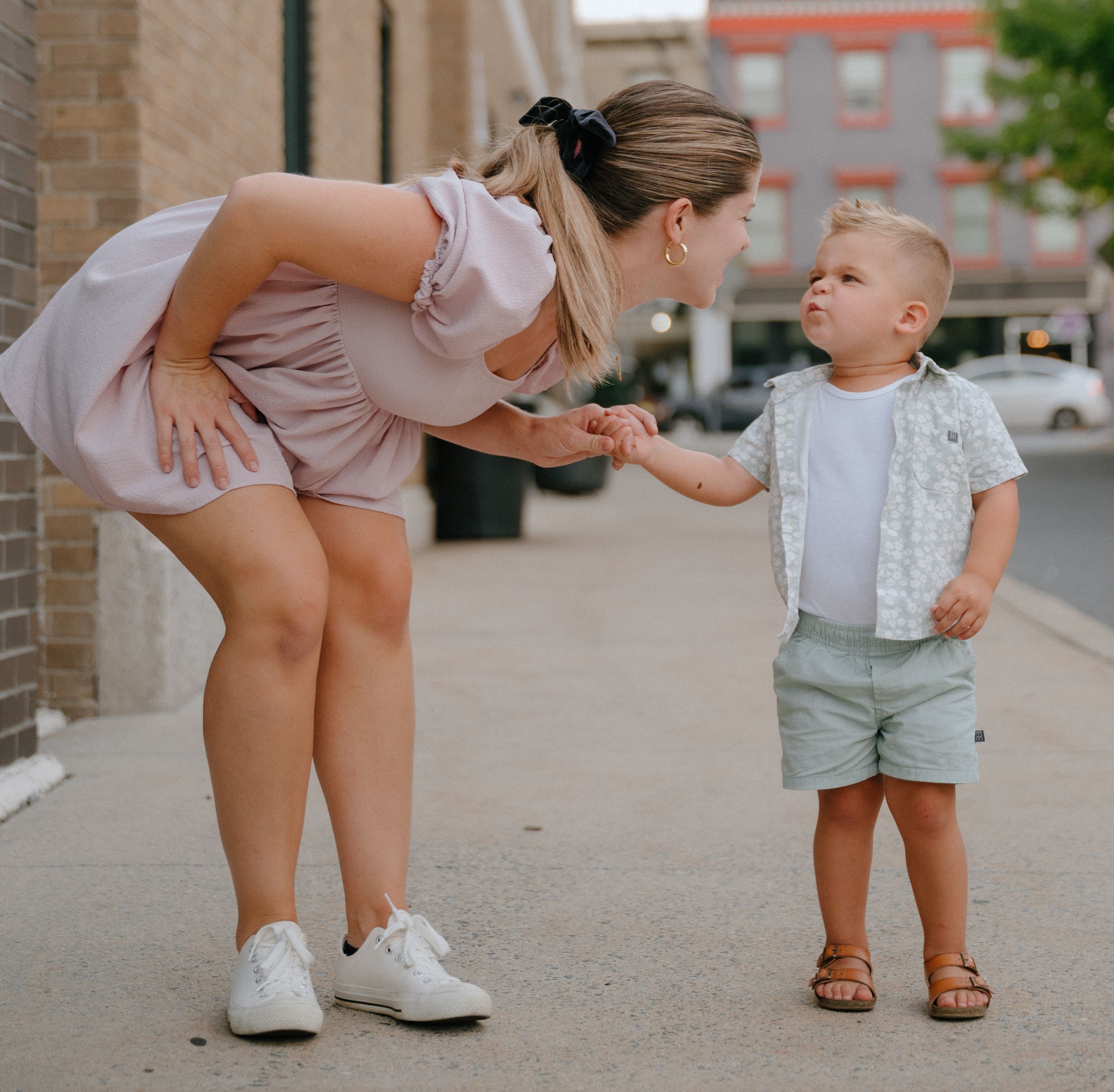 An endearing interaction between parent and child on an urban sidewalk.