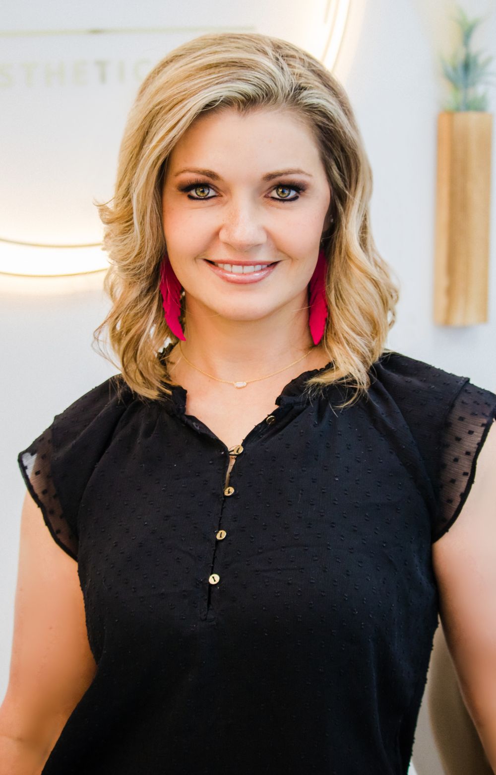 Professional headshot with black top and red statement earrings.