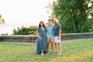 Family standing together on grassy lawn with mountain view in background.