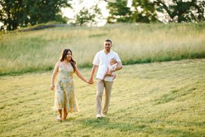 Family walking together on grassy hillside during golden hour.