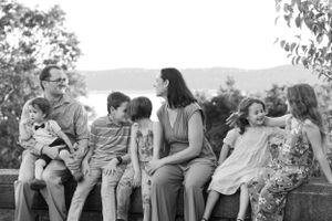 A group sits together on stone wall with mountain vista in background.