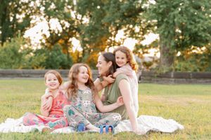 A family group poses together on a blanket outdoors during sunset.
