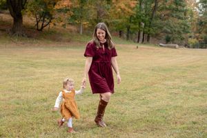 A couple walks together through a scenic autumn park with fall foliage in the background.