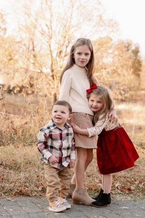 Children in autumn attire playing and hugging outdoors.