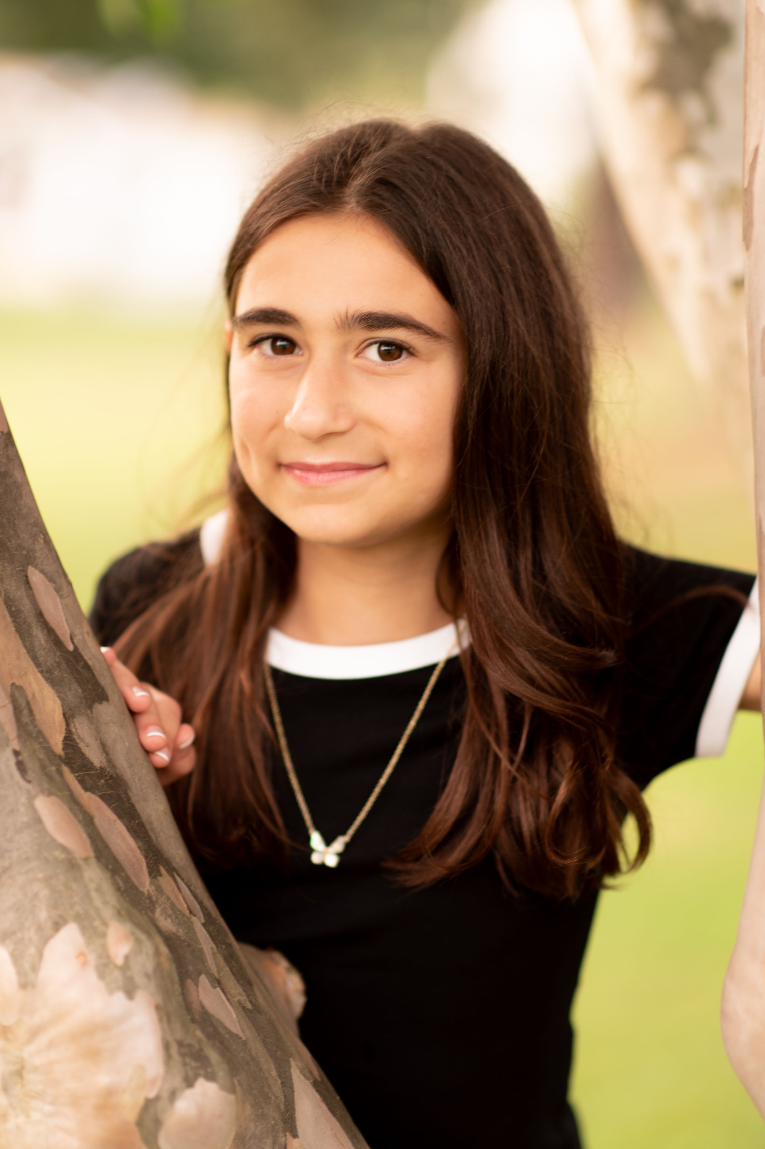 A series of four photos showing someone with long dark hair wearing a black sweater posing outdoors against a blurred background.