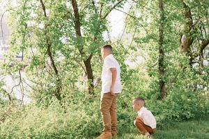 A couple shares a romantic moment in a sunlit forest setting during an outdoor photo session.