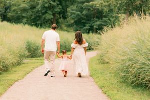 Family walking together on nature path holding hands.