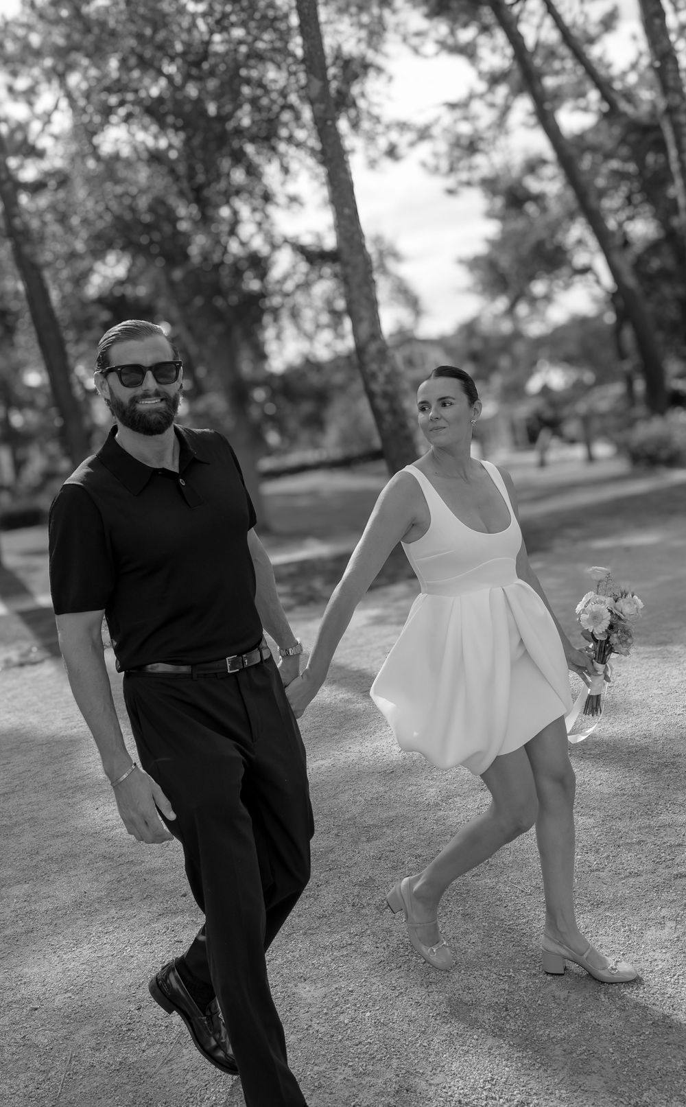 A black and white photo series showing two dancers performing expressive movements together in a park setting.