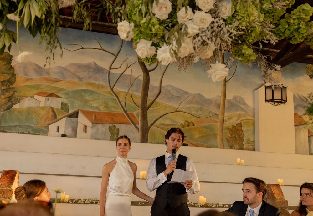 Restaurant service staff standing in front of a pastoral wall mural during an indoor event.