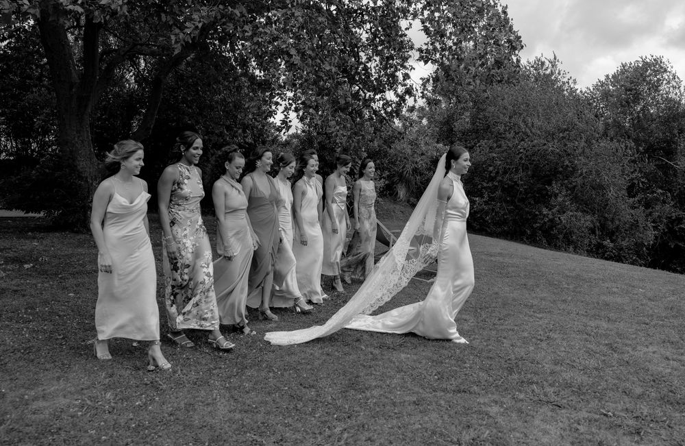 A panoramic sequence of people in formal attire walking and posing together on a grassy hillside during an outdoor event.