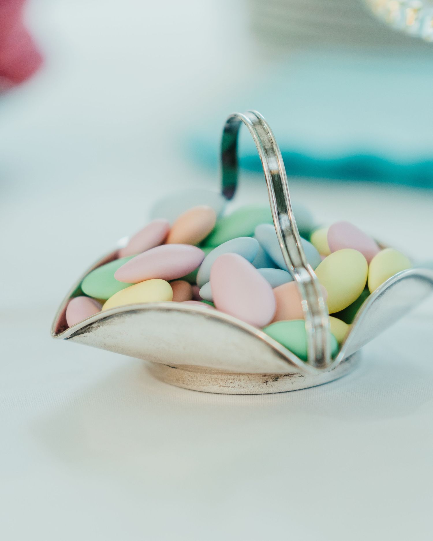 Pastel Jordan almonds served in a silver dish at a wedding reception.
