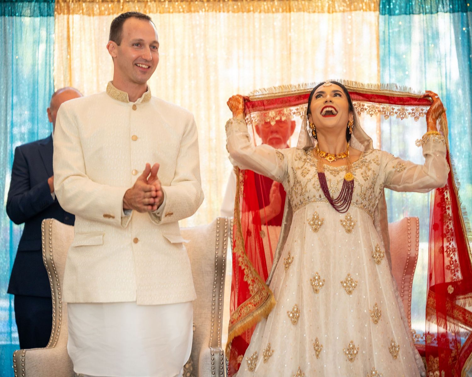 Joyful wedding celebration with couple in traditional Indian and Western fusion attire.