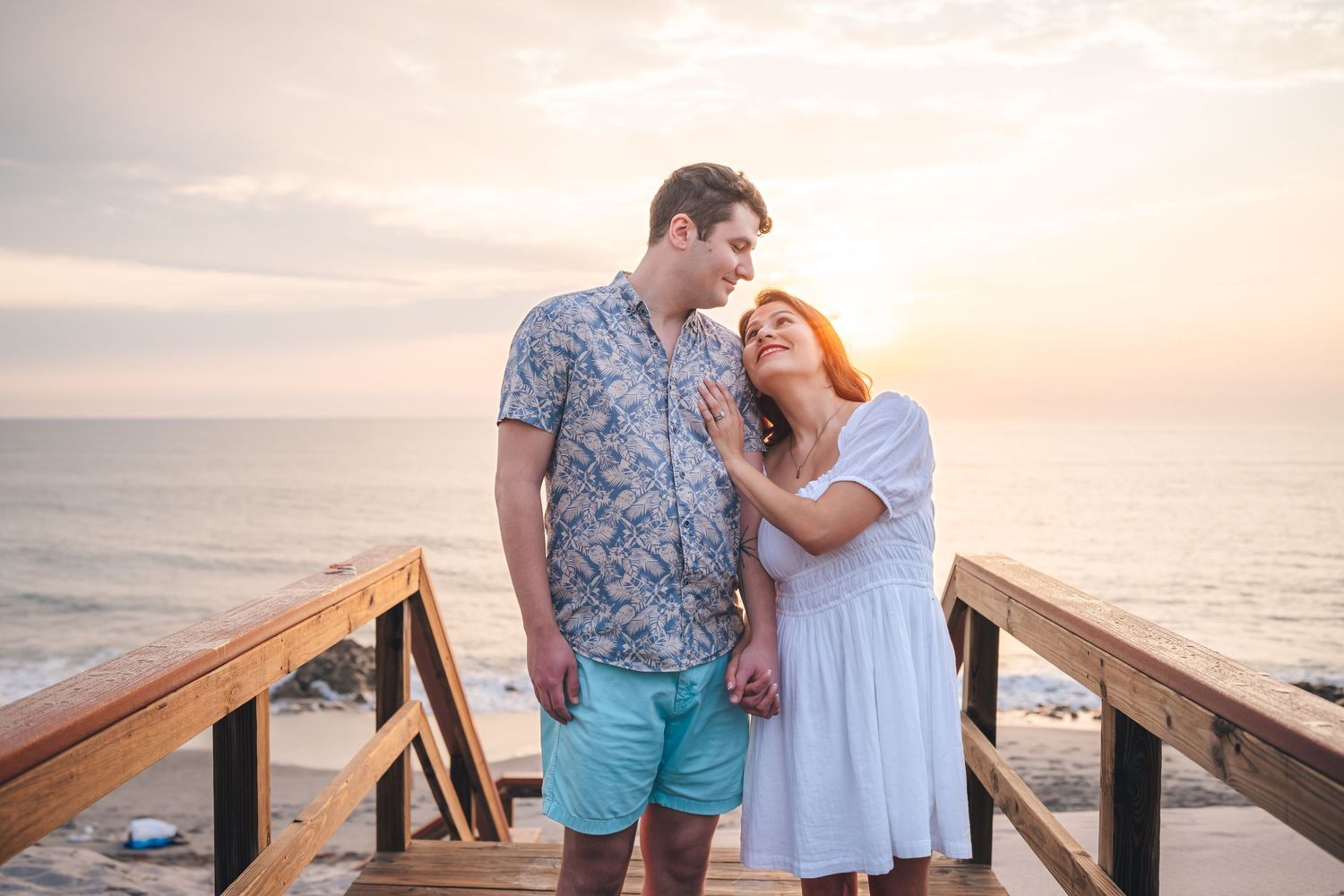 Happy couple sharing a romantic moment at sunset on a wooden deck by the ocean.