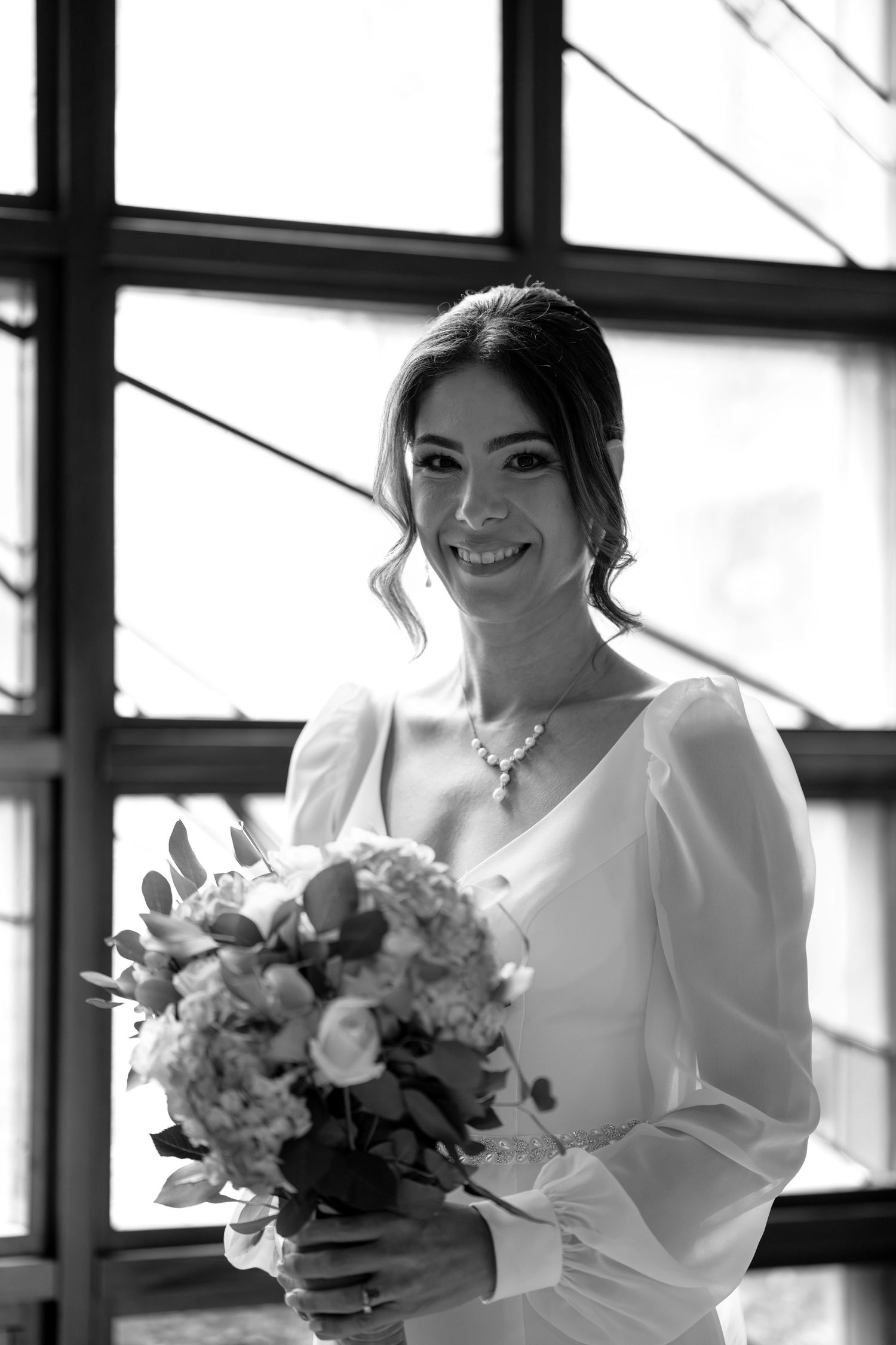 Black and white portrait of bride holding bouquet and wearing classic white gown.