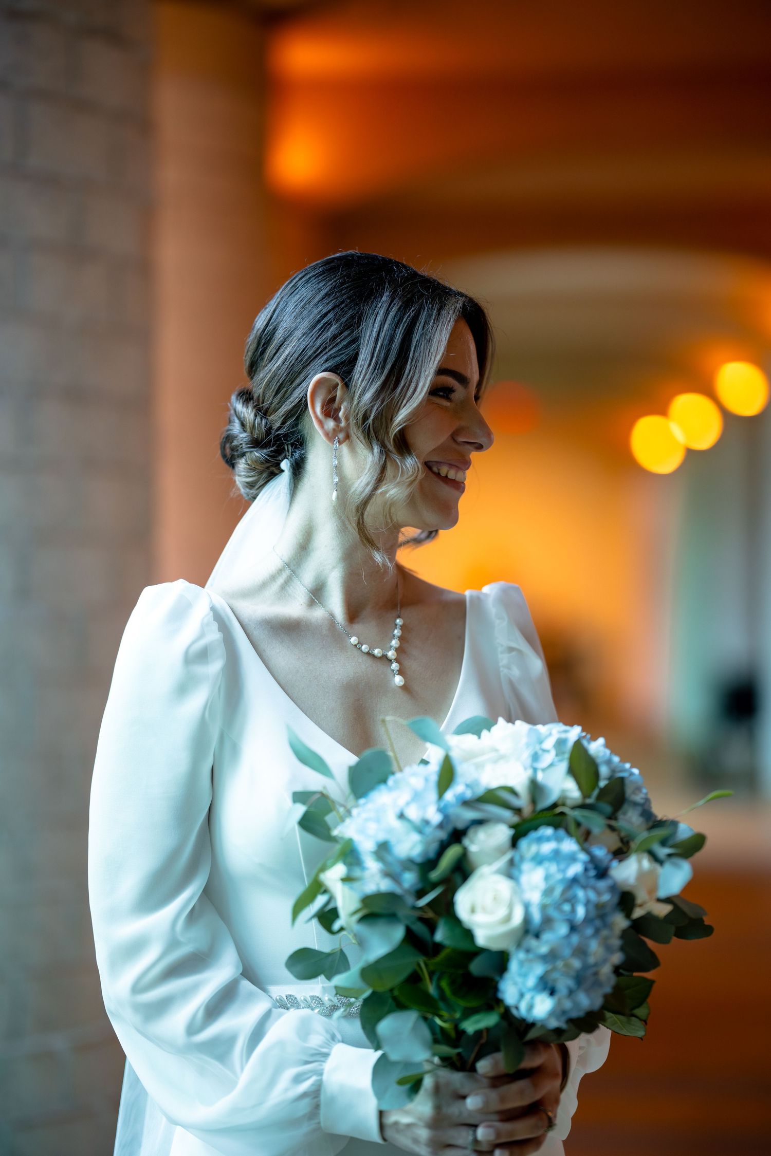 Bride in elegant white dress with puff sleeves holding blue and white bouquet.