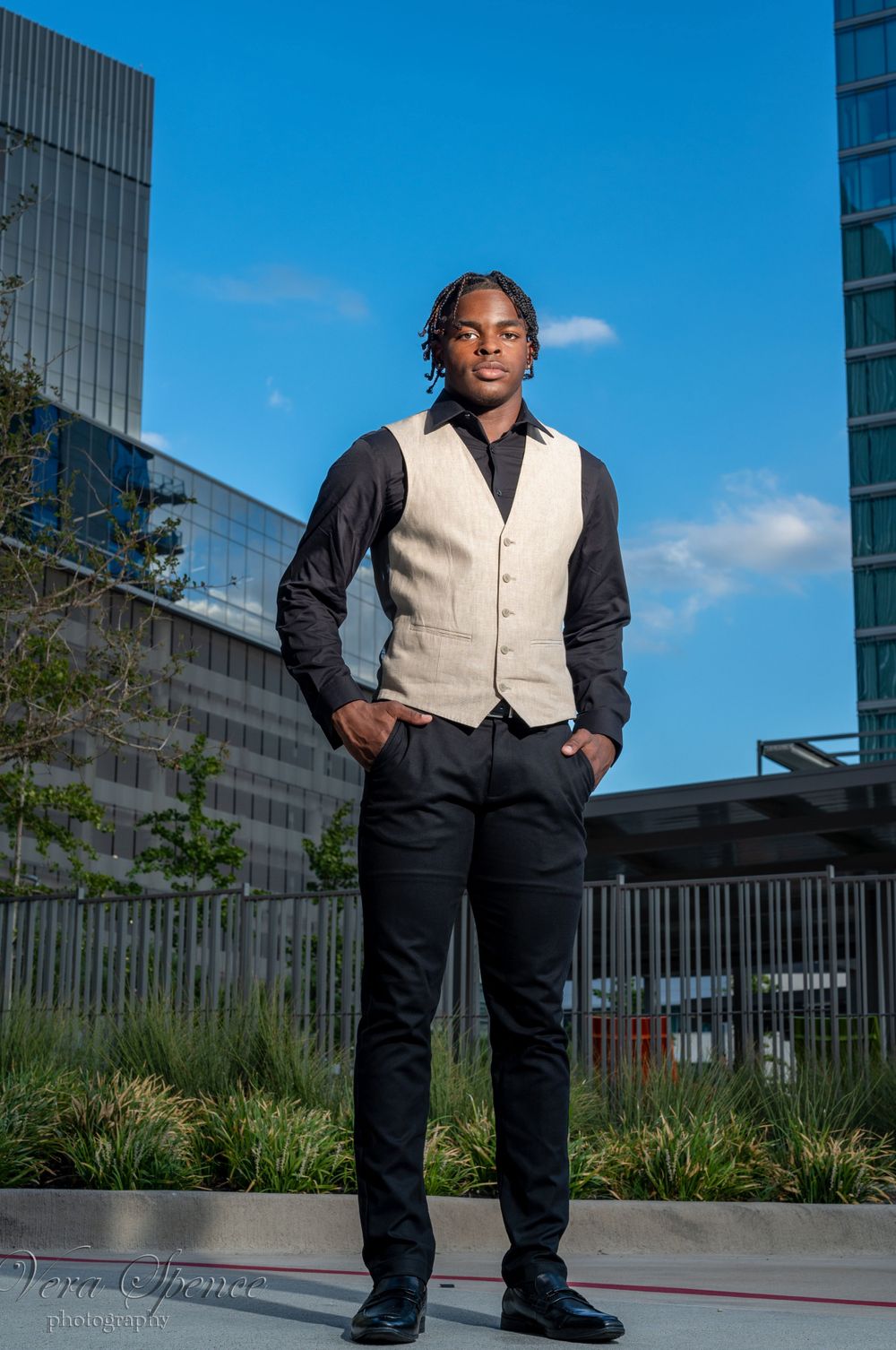 Professional senior portrait of person in business attire against urban backdrop with modern buildings.