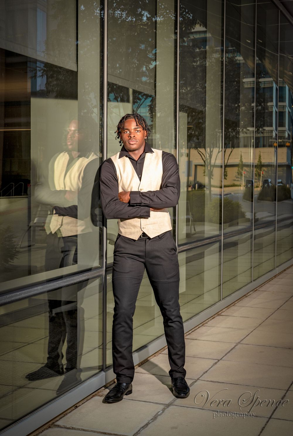 Stylish teen portrait against reflective glass building exterior.