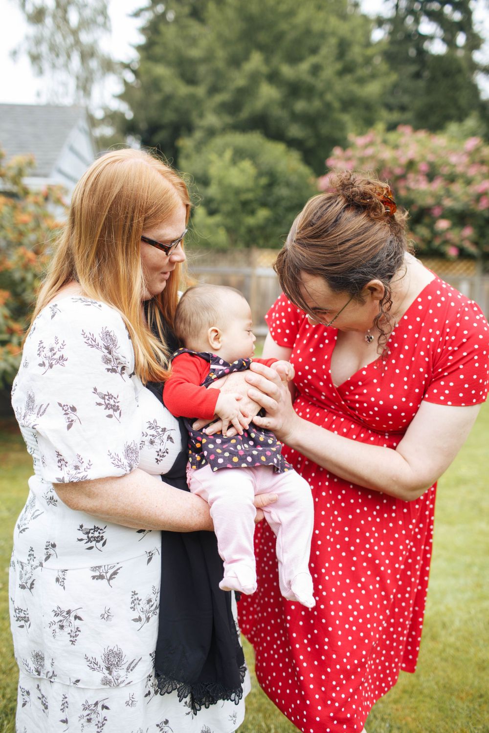 mukilteo family photographer: two mother pose with their newborn daughter at their backyard family photo session