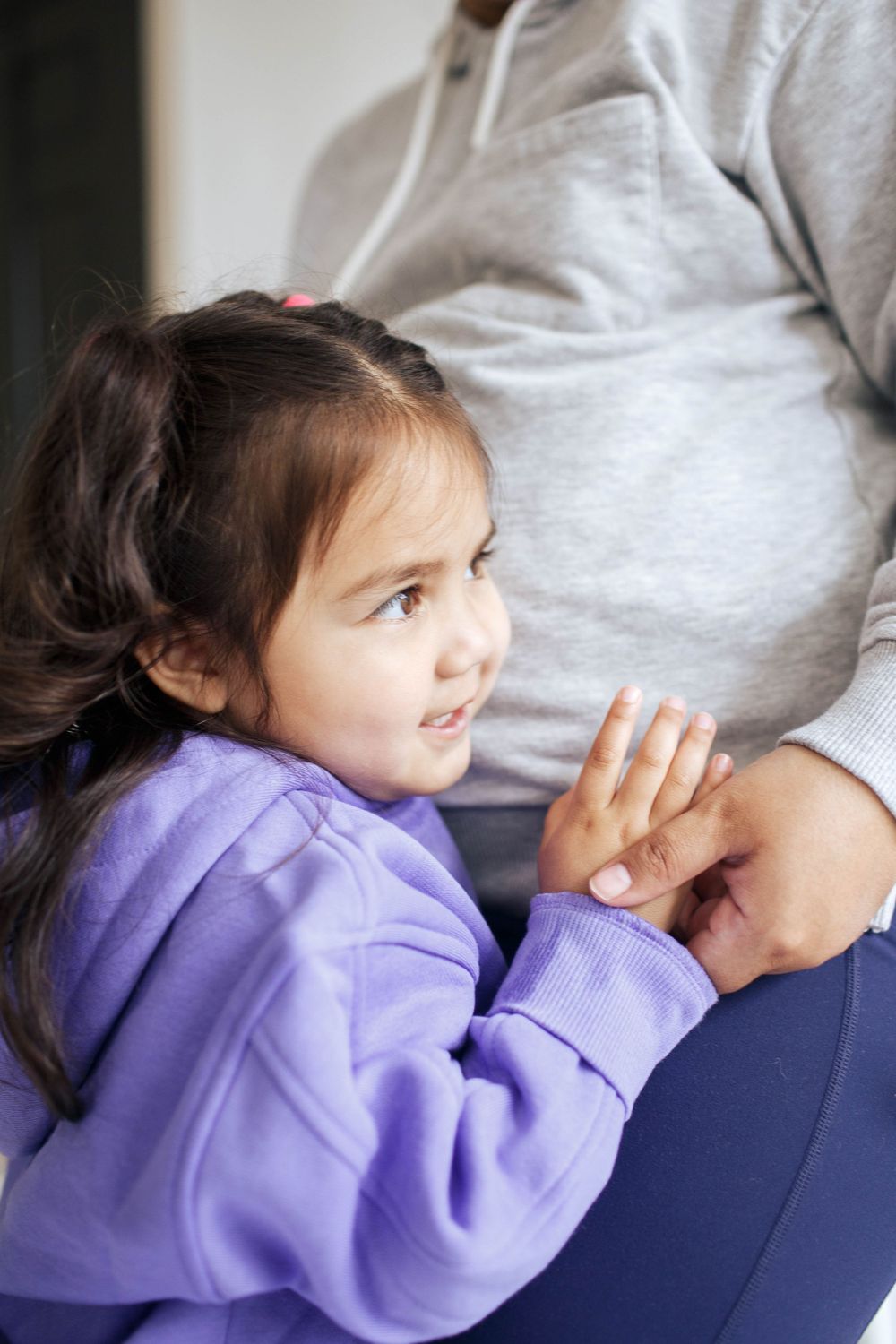 everett family photographer: a young girl places her head on her mom's belly at a family photography session at home