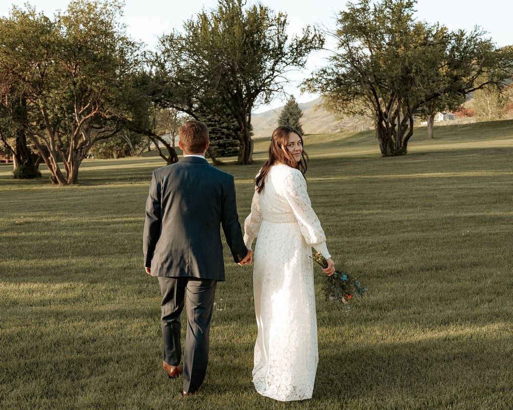 Logan UT bride looking back at camera as she walks with groom at their Cache Valley venue.