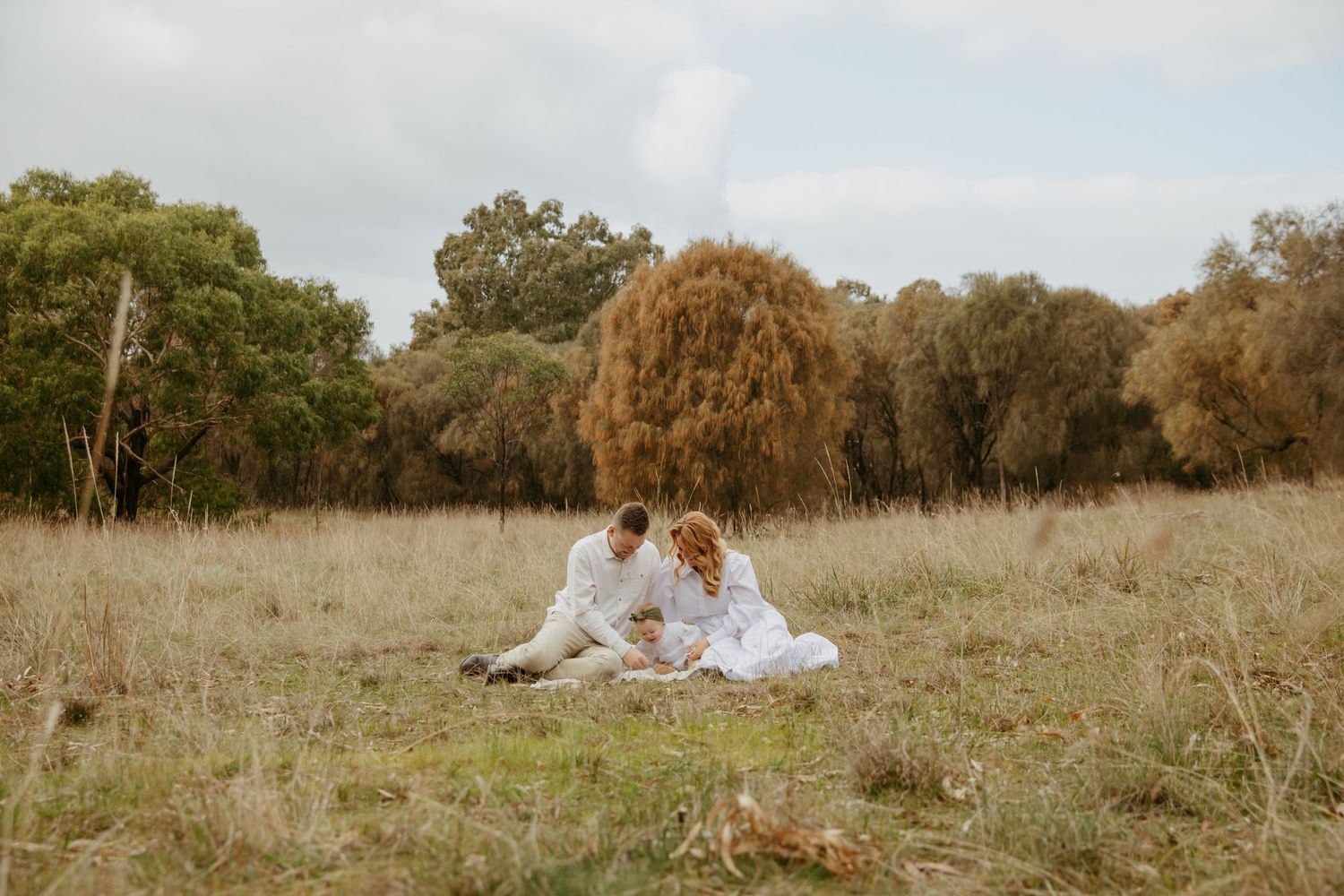 family on picnic rug in the bush, playing with their baby, Teesdale