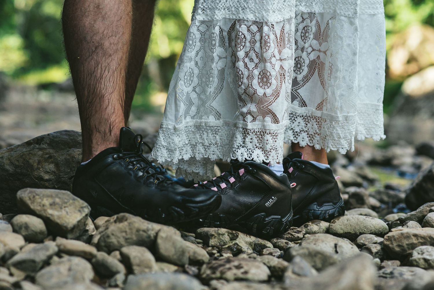 Contrasting hiking boots and lace dress hem against rocky terrain.