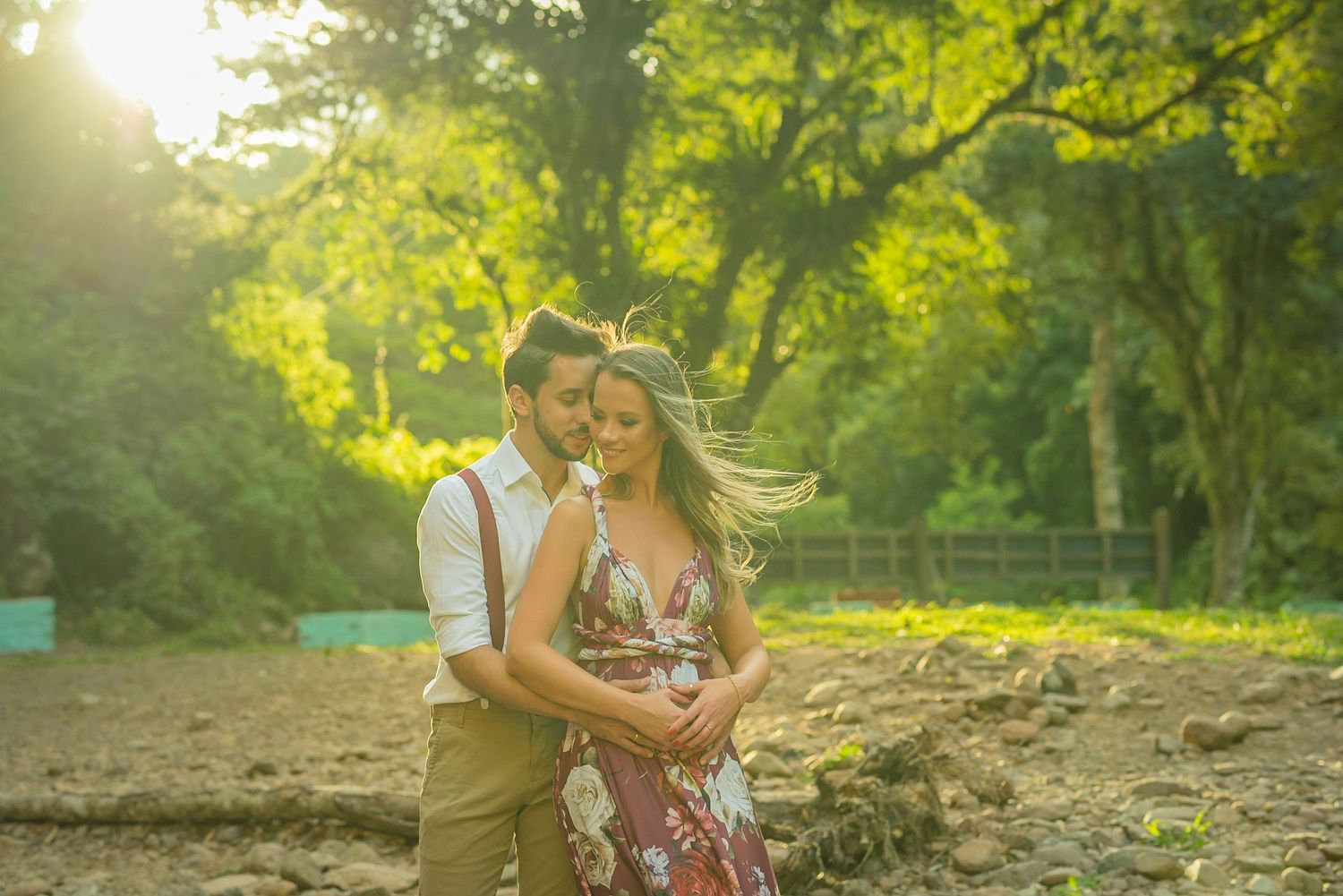 A romantic sunset photoshoot in a wooded park with golden light filtering through the trees.