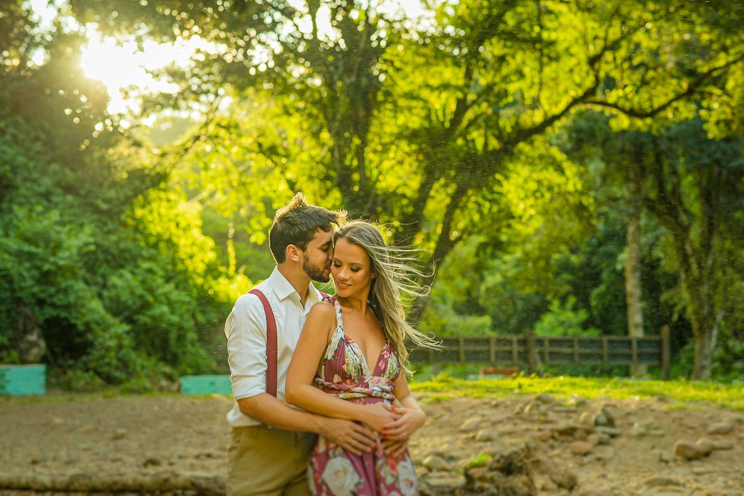 A tender embrace captured in golden hour lighting with lush greenery in the background.