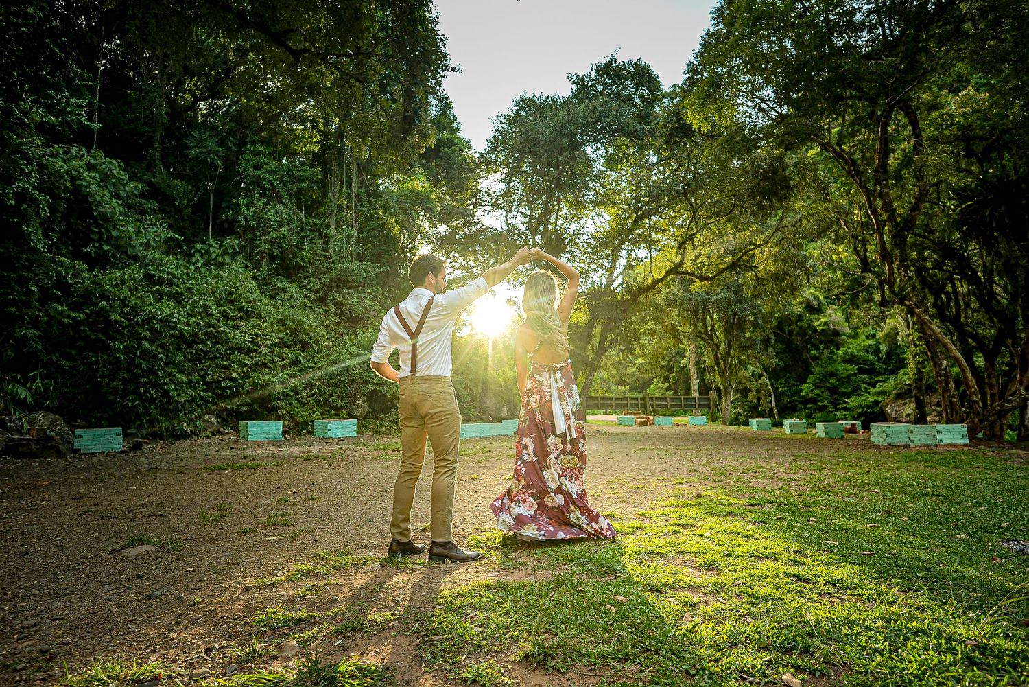 A romantic photoshoot in a wooded park with sunlight streaming through the trees.