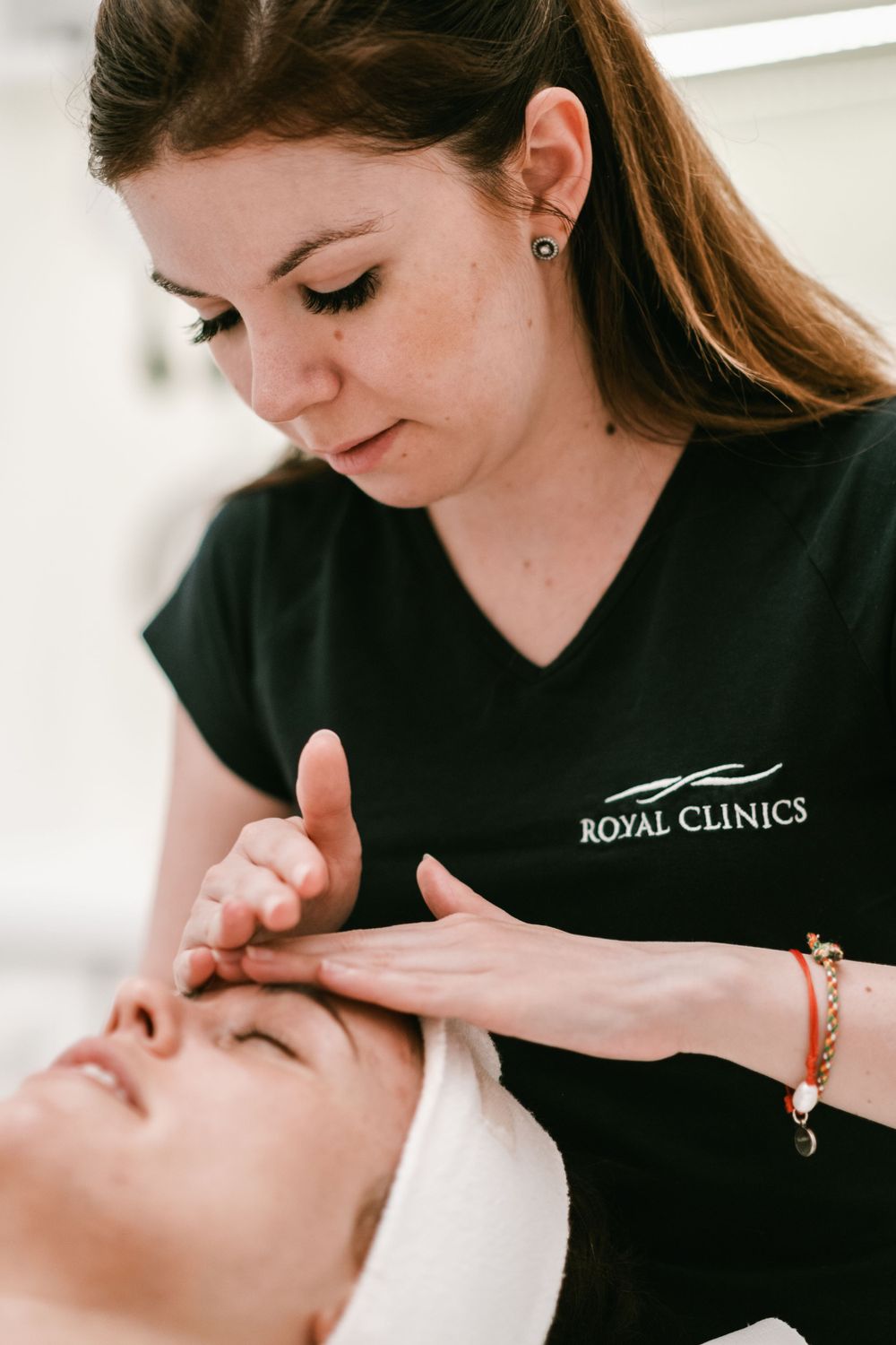 Facial treatment being performed by spa technician wearing Royal Clinics uniform.