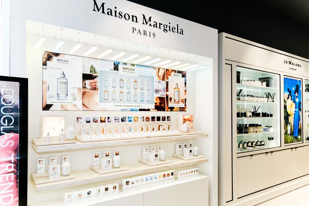Clean white luxury fragrance retail display with backlit shelving.