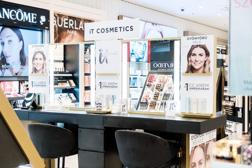 Wide shot of a modern beauty retail space with illuminated brand displays and makeup counters.