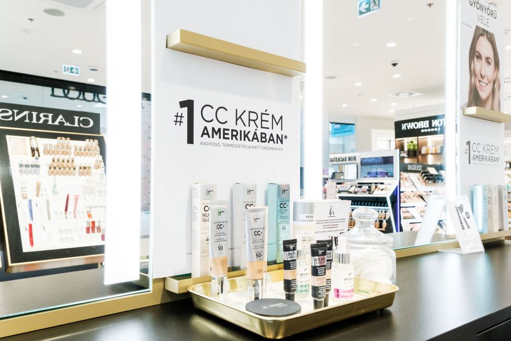 Bright retail display showing various CC creams and cosmetic products on white shelving.