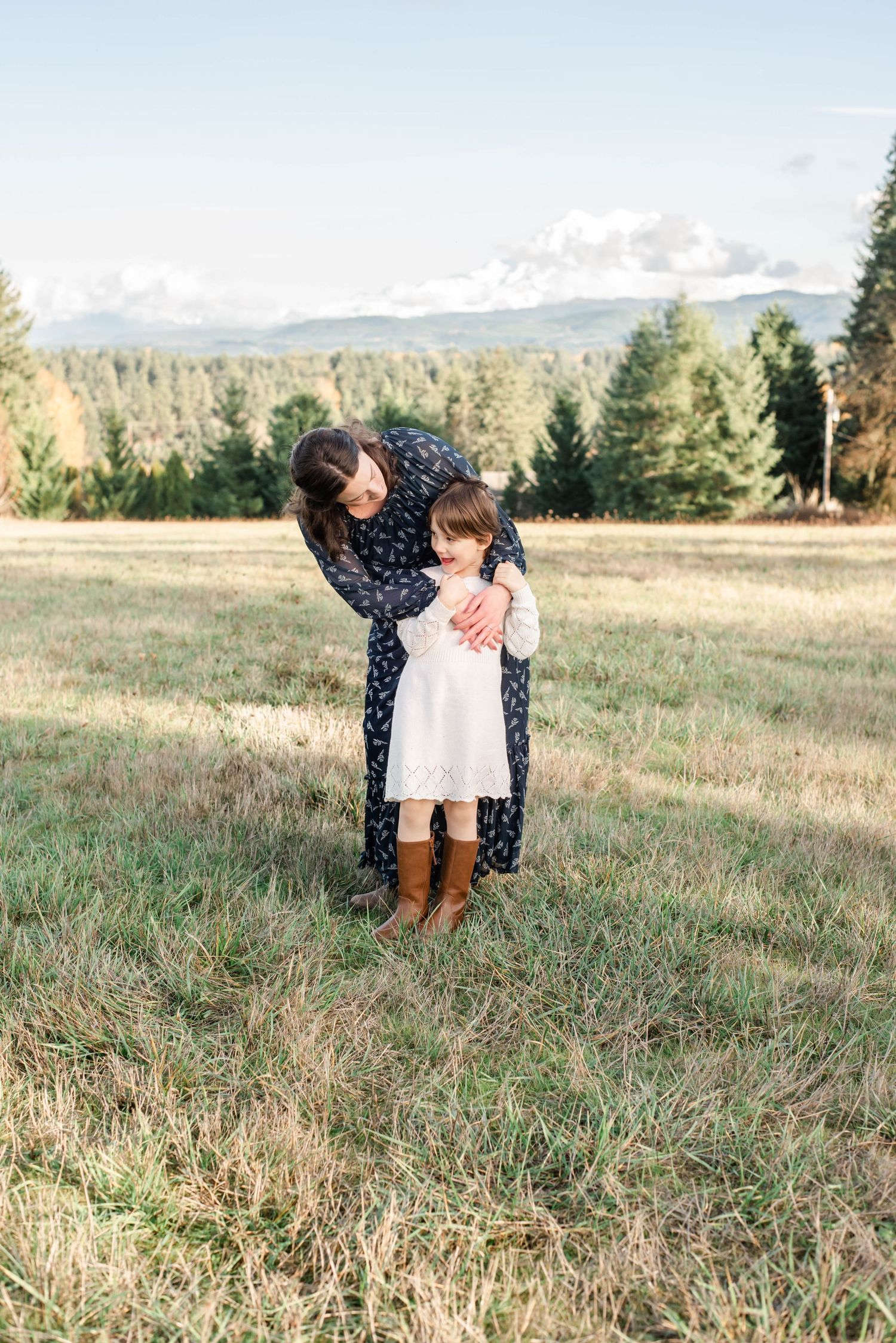 Family sharing playful moment together in mountain meadow at sunset.
