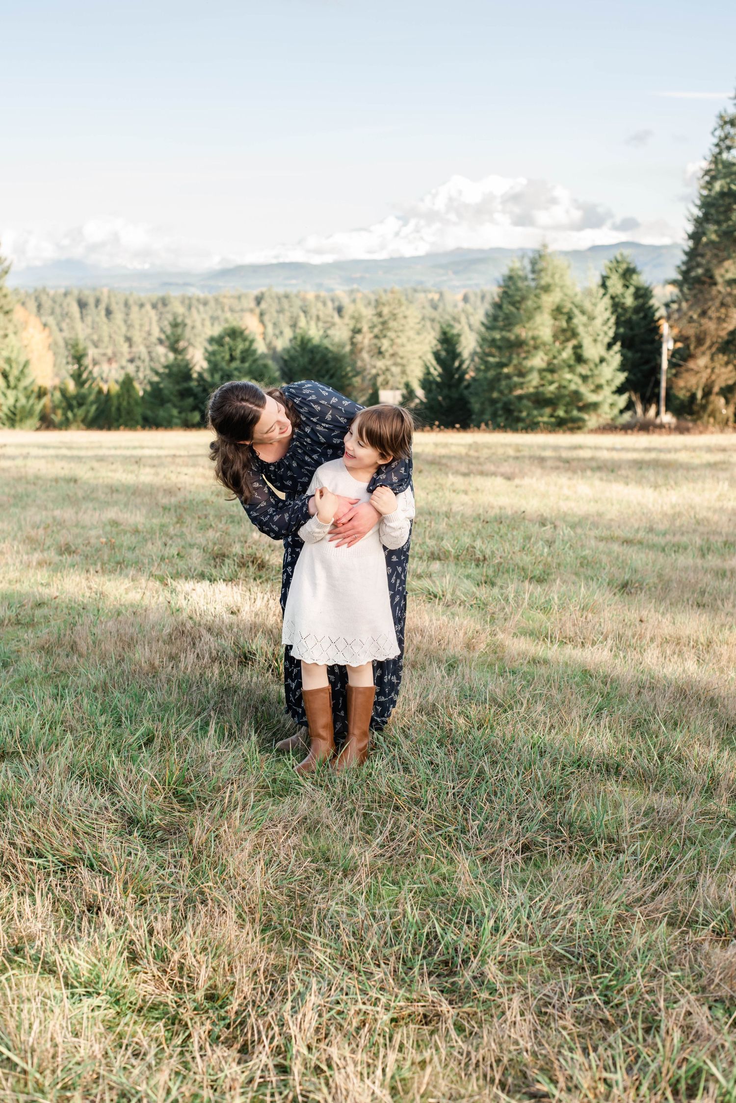 Candid family moments captured in golden hour light on grassy hillside.