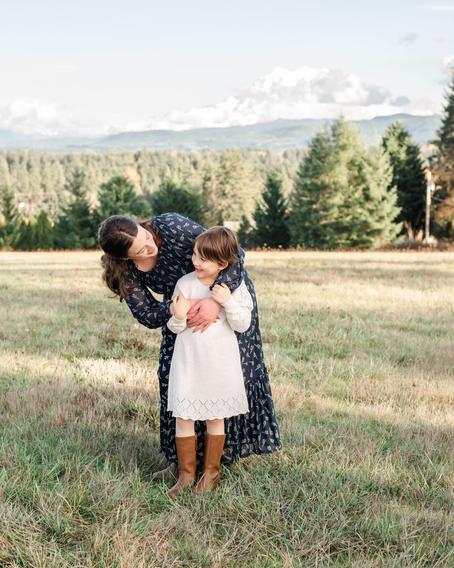 Sweet family moment captured in natural meadow setting with mountain views.
