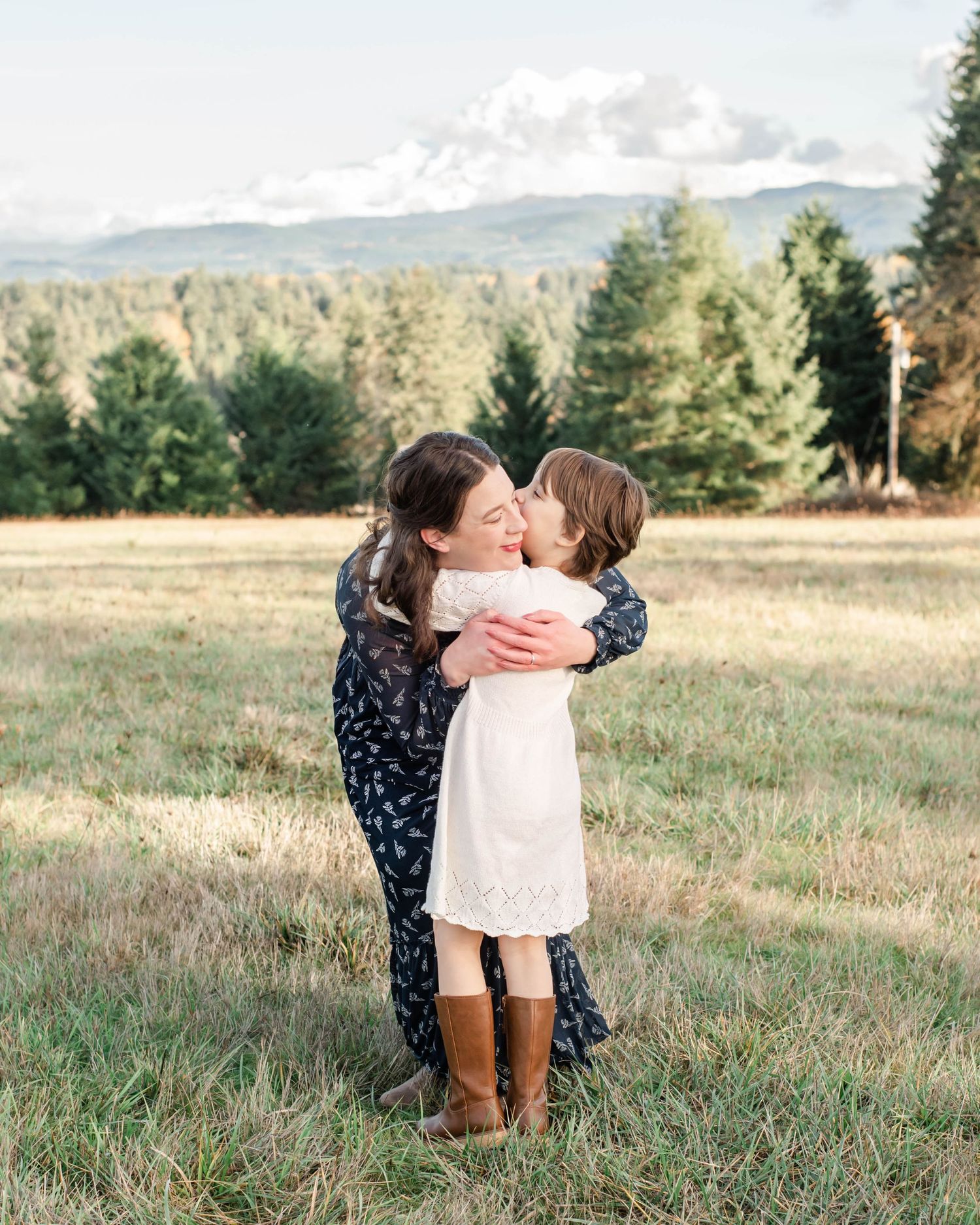 Tender family embrace photographed in rustic mountain meadow setting.
