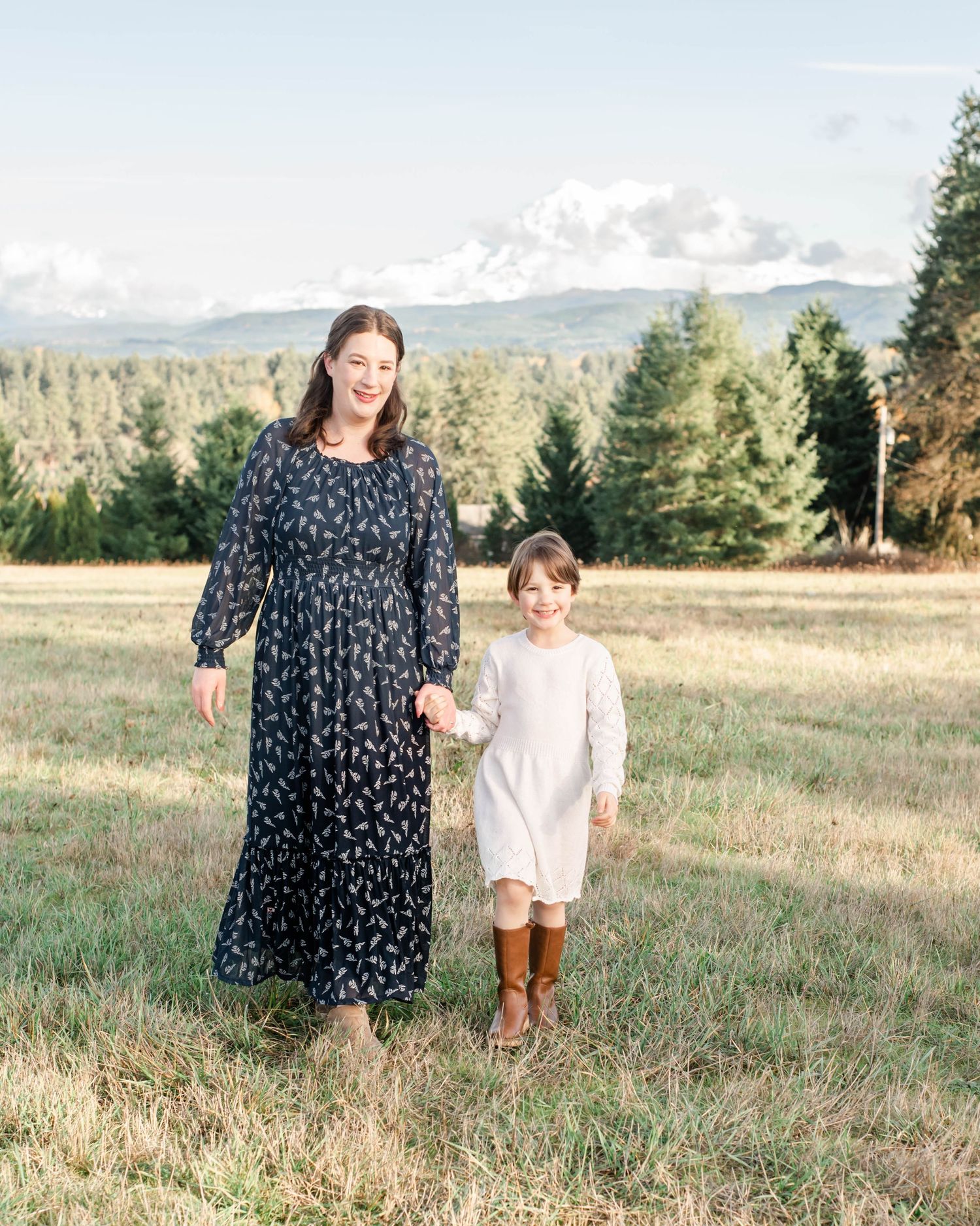 Candid lifestyle photos of a parent and child walking through a golden grassy field at sunset.