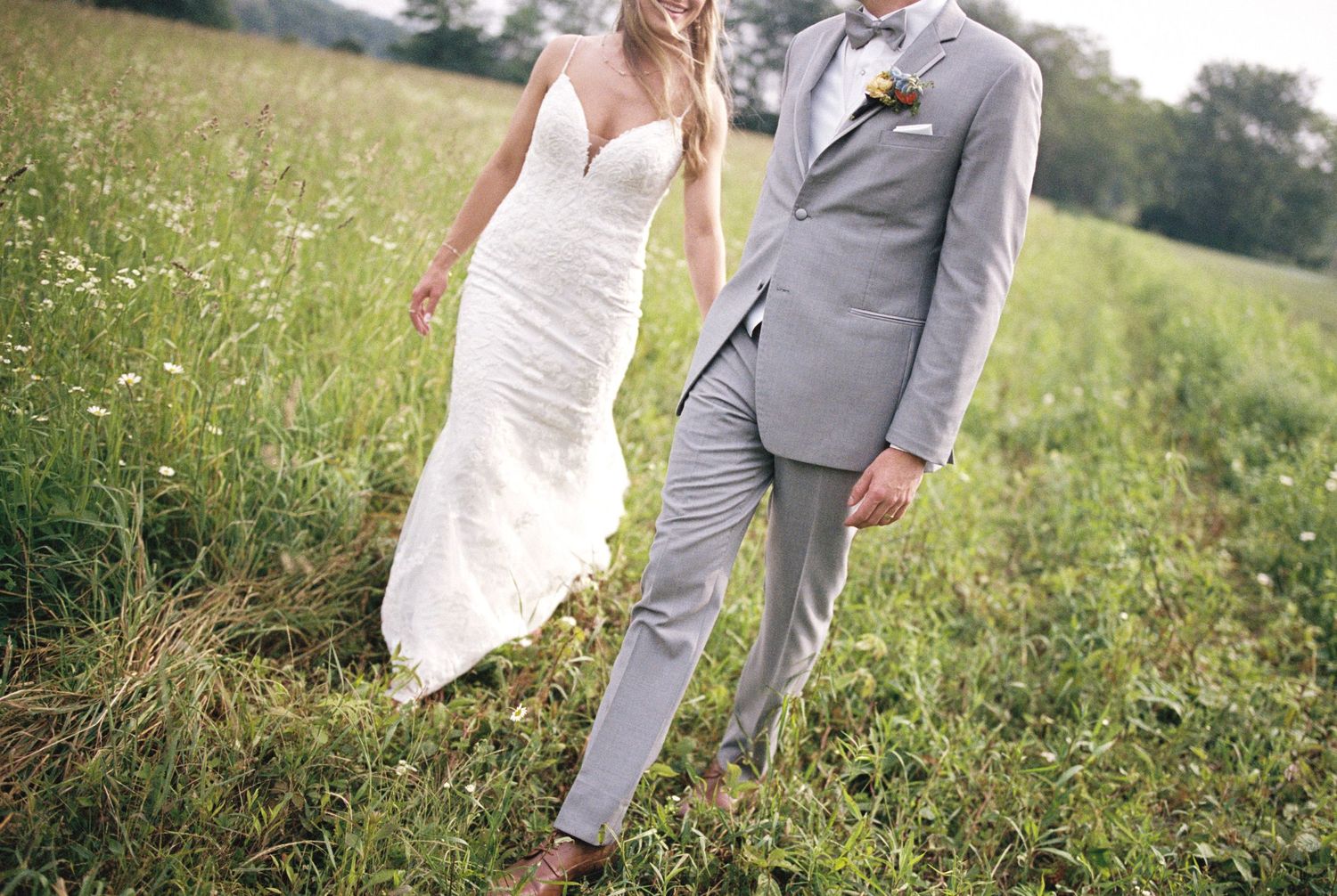 Close-up of bride and groom's feet dancing on cobblestone, with white dress flowing.