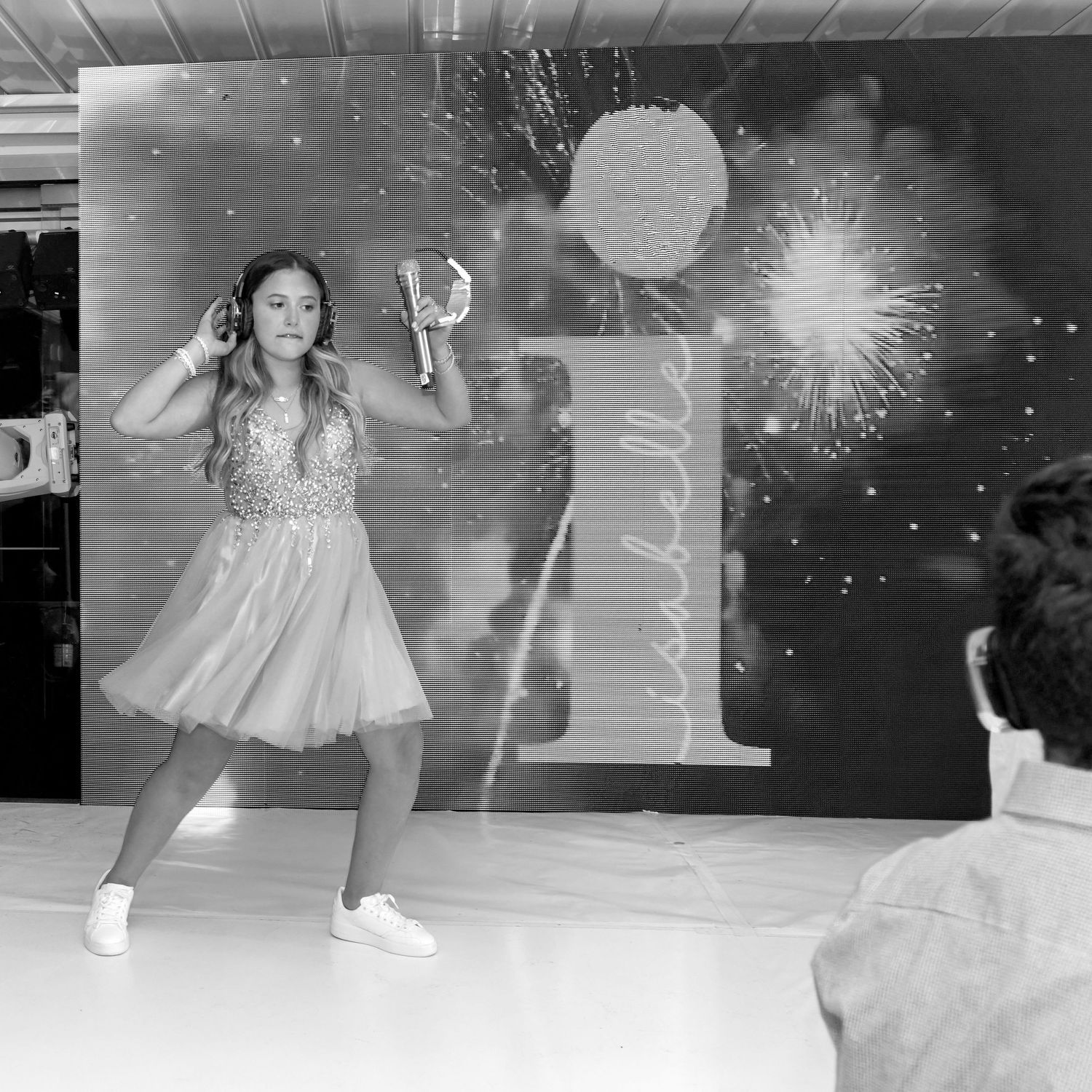 A black and white photo of someone in white sneakers dancing on a reflective surface with dramatic lighting.