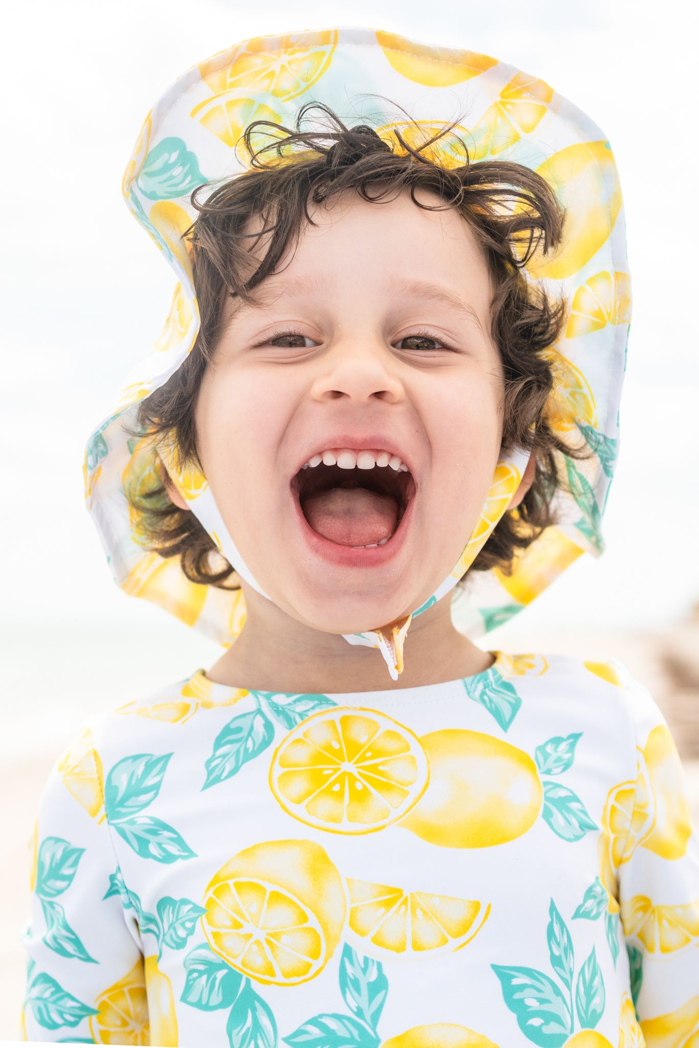 A joyful expression of pure happiness captured in bright lighting against a lemon-print patterned clothing background.