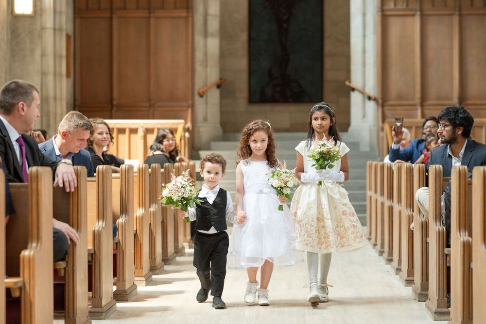 Young ring bearer and flower girls walk down the church aisle during a wedding ceremony.