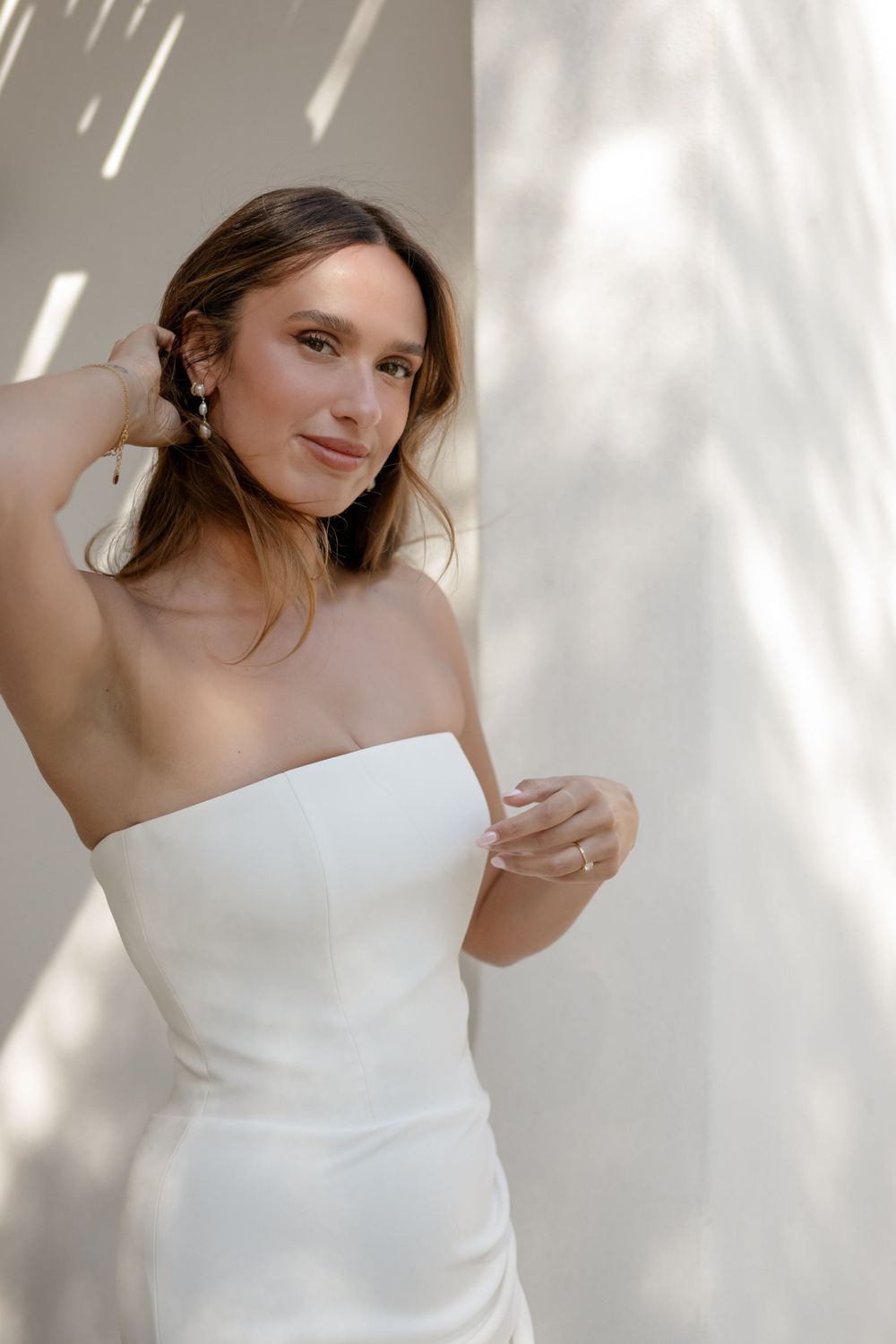 A series of soft, minimalist portraits featuring someone in a white off-shoulder top against a light background with dappled shadows.