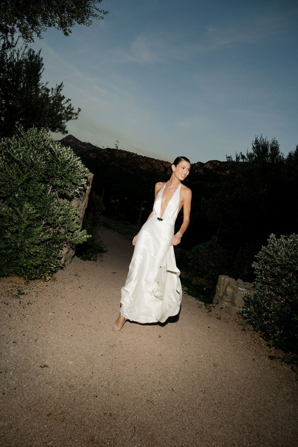 A sequence of photos showing someone in a white wedding dress walking along a desert path at dusk.